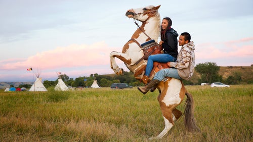 Stevana Salazar (left) of the Kickapoo Tribe of Texas rides with Arlo Standing Bear, Oglala Lakota from Allen, South Dakota. Horses are ubiquitous in camp, as riders keep the peace, scout for activity on the pipeline, and compete in races and games.