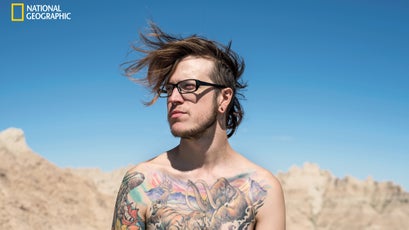 On an annual backpacking trip to South Dakota with three friends, Andrew Notsch basks in the sun at Badlands National Park. The prehistoric creatures on his tattoos are reminiscent of remains found in the park’s rich fossil beds, such as a saber-toothed cat.