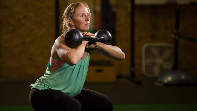 Wright performing a front squat with kettlebells.