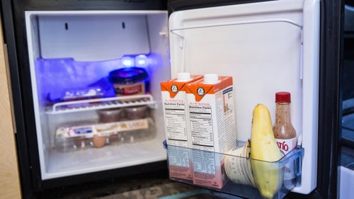 Inside the fridge: hummus, hot sauce, eggs, squash, and milk.