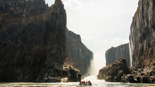 The Zambezi’s natural flow fluctuates a great deal. During the dry season (North America’s summer), Victoria Falls appears as a long escarpment of veil-like cascades, while in the rainy season, the entire canyon is a tumultuous and thundering chaos. The proposed Batoka Dam, 34 miles downstream, would create a reservoir that would lap at the bottom of Victoria Falls, possibly reducing its height. Our raft trip began just below the falls, after a 20-minute descent on foot.