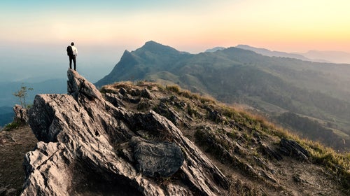 man standing on a ridgeline at sunset