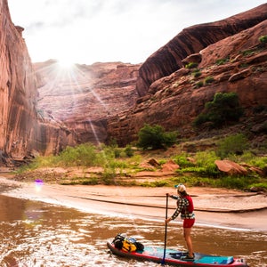 This May, five adventurers pushed off below the bridge at Highway 12 in southern Utah to navigate a 100-mile stand-up paddleboard first descent on the Escalante River, which drains into Lake Powell. The caravan, composed of Dylan Brown, Morgan Tilton, Jordan Curet, Morgan Smith, and Aaron Kloer—all seasoned outdoor explorers but novice boaters—made hundreds of hook turns for six days through Grand Staircase-Escalante National Monument’s soaring Navajo sandstone. The gorge reached heights of more than 1,000 feet and greeted the crew with boulder-strewn whitewater.
 
Here, Morgan Tilton takes us through a few of Dylan Brown's favorite shots from the trip.
Photo: Tilton admiring one of the many stunning horseshoe bends in a series of progressively taller, more pronounced 180-degree curves near the halfway point on the Escalante. She rode the inflatable Hala Gear Straight Up, which is durable and stable, with fully removable fins and well-placed reinforced stainless D-rings for strapping down gear.
