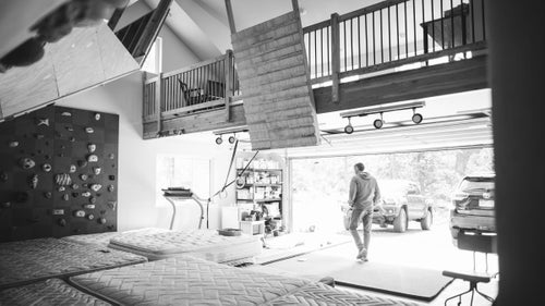 The garage has been converted into a massive climbing gym, with six full-size mattresses and three walls.