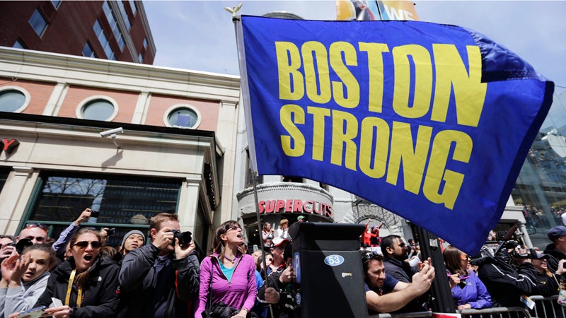 Race fans with a "Boston Strong" flag cheer for competitors near the finish line of the 118th Boston Marathon, Monday, April 21, 2014, in Boston. (AP Photo/Robert F. Bukaty)