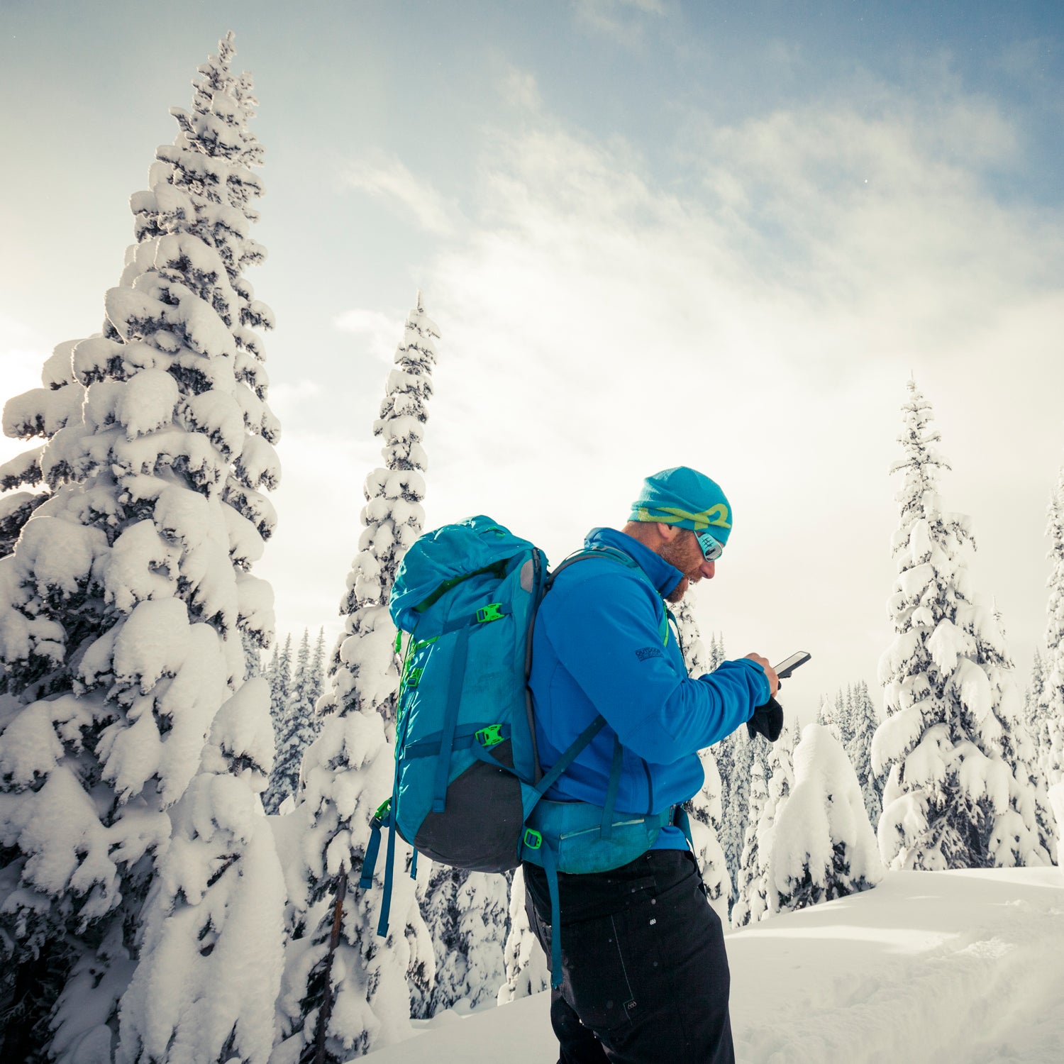 Skier Stops To Checking His Smartphone During A Backcountry Ski Trip