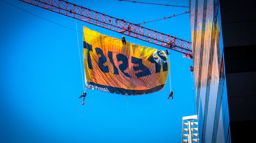 Greenpeace protestors unfurl a banner reading 