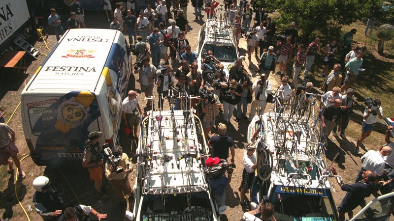 Journalists, riders, and support staff gather around the Festina vehicles involved in the team doping scandal.