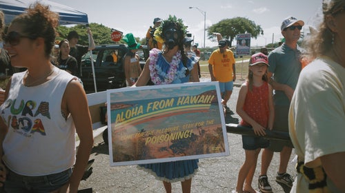A young woman protests GMO seed testing in Maui, where a similar debate about GM crops is taking place as the one in Kauai.