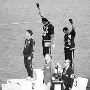 Tommie Smith and John Carlos, gold and bronze medalists in the 200-meter run at the 1968 Olympic Games, engage in a victory stand protest against unfair treatment of blacks in the United States. With heads lowered and black-gloved fists raised in the black power salute, they refuse to recognize the American flag and national anthem. Australian Peter Norman is the silver medalist.