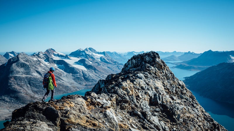 Andrew summits a peak with Tasiilaq Fjord in the distance. Has anyone been up here before? Has anyone taken this route to the top? It's impossible to know for sure.