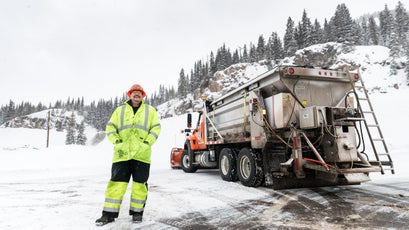 Klein stands by as workers trigger avalanches above the road.