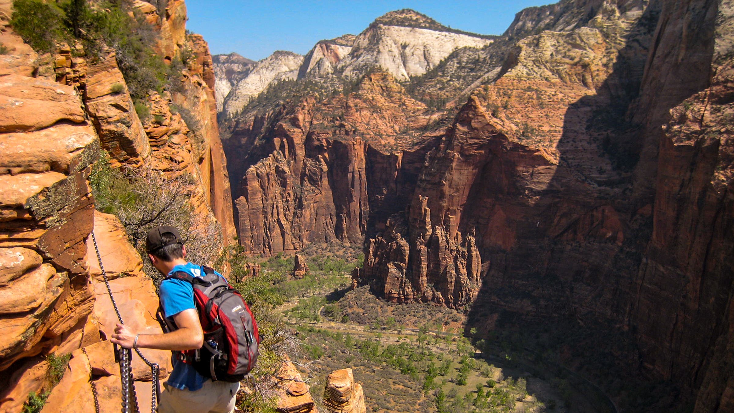 A hiker descends the Angels Landing route in Zion National Park with near 1000 foot drops on both sides.