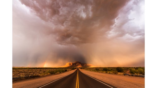 Heavy rain falling around the Superstition Mountains east of Phoenix as the setting sun illuminates the storm.
