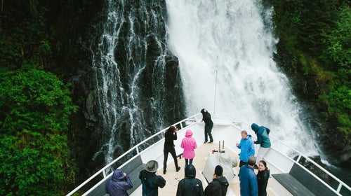 Tourists marvel and take photos of a waterfall in Red Bluff Bay off the bow of an Alaskan cruise ship.