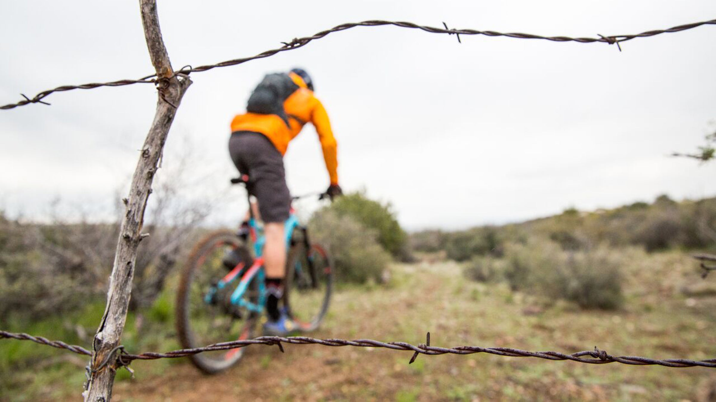 A mountain biker rides past barbed wire on the historic  Black Canyon Trail in Arizona. 