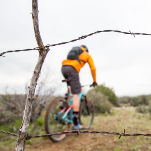 A mountain biker rides past barbed wire on the historic  Black Canyon Trail in Arizona.
