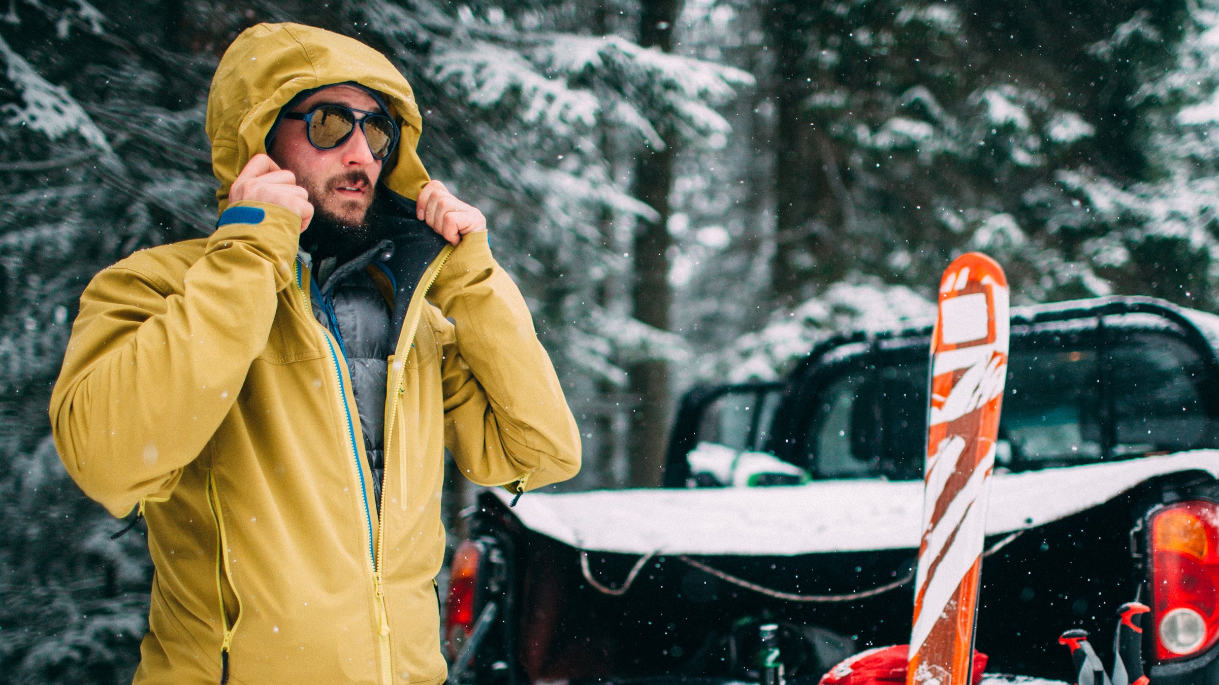 Young man with ski in the snow forest standing near the car