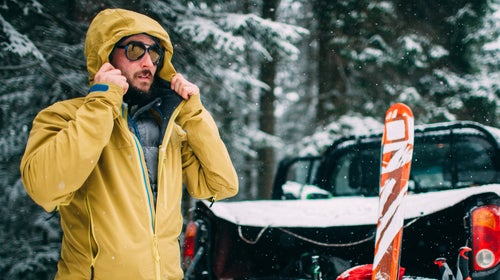 Young man with ski in the snow forest standing near the car