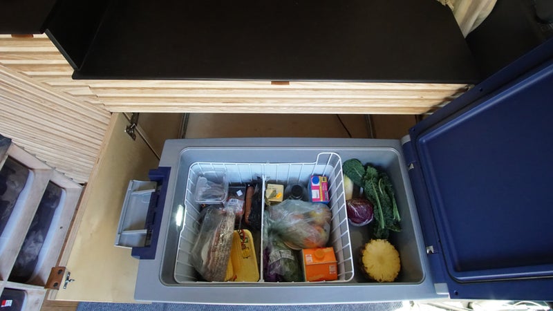 An ARB refrigerator/freezer runs on the vehicle's 12V electrics, and allows the couple to keep food fresh indefinitely. It's just like your fridge at home, just a little smaller. Tommy built a custom slide-out cabinet to store it, under their countertop.