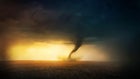 A tornado in a field at sunset.