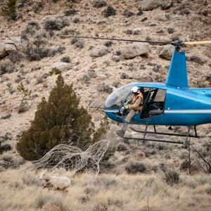 The Wyoming Migration Initiative (WMI) is composed of researchers, writers, students, and conservationists who strive to advance the understanding of the state’s migratory deer and bighorn sheep. Increases in private housing developments, traffic, and energy extraction on our public lands have threatened many ungulate migration routes in Wyoming. 
For a week in March, photographer Ben Kraushaar shadowed the WMI folks as they captured and collared 35 Rocky Mountain bighorn sheep and 220 mule deer throughout Wyoming. From the Red Desert to eastern Greater Yellowstone, Kraushaar documented the steps involved in WMI’s efforts to better understand the migrations and health of these animals. Here, Kraushaar shares a behind-the-scenes look at the fast-paced life of wildlife biologists collecting invaluable data in the field. 
Kevin Coates, who works for Native Range Capture Services, nets a bighorn sheep.  Once netted, the mugger (the person who subdues the animal) jumps from the chopper and carefully hobbles and blindfolds the sheep. For deer and sheep, sedation is usually unnecessary. Coates then carefully prepares the animal for transport to a nearby field research setup.