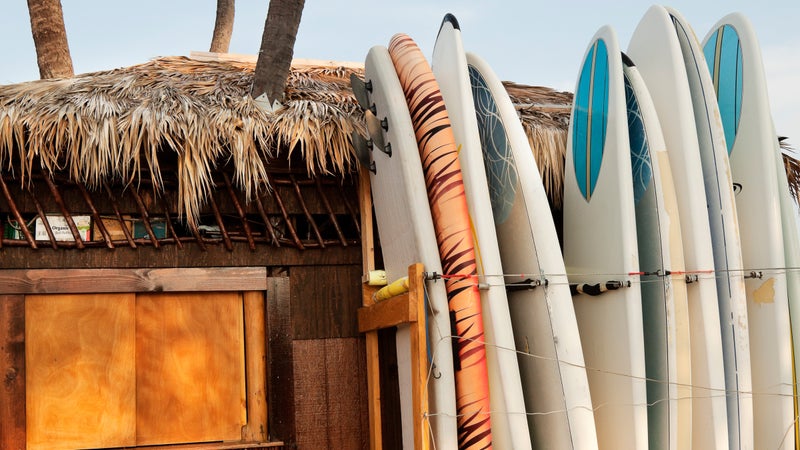 Paddle boards rest against a tropical hut in Kona.