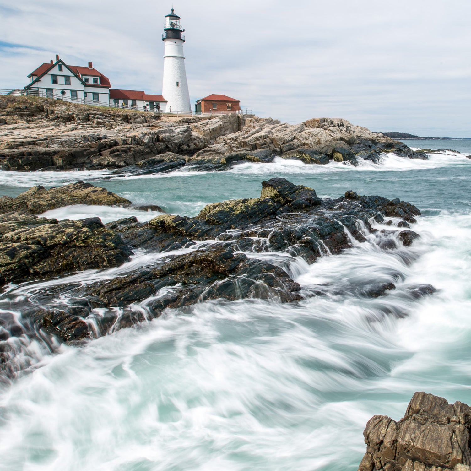 The famous lighthouse at Portland Head rests confidently above the crashing surf in Cape Elizabeth, ME.