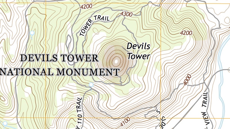 And here is Devil's Tower on a proper USGS topo map. You can immediately see how much more information is available, describing even hitherto unseen terrain features surrounding the butte, which rises steeply in the middle of the map. The farther apart the contour lines, the more gradual the slope; the closer they are, the steeper the slope. As you can see in the photograph up top and on this topo map, Devil's Tower rises almost vertically. On this map, the contour interval is 20 feet, meaning each line is 20 vertical feet from the next one. You can see valleys formed by contour lines making a "V" pointed uphill, while ridges make a "V" pointed down. Peaks are represented by rough circles, as on Devil's Tower.