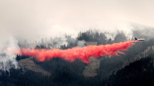 A bomber drops a load of fire retardant below the Lolo Peak fire creeping down the face of the ridge toward the Bitterroot Valley, Friday, Aug. 18, 2017 in Missoula, Mont. more homes west of the town of Lolo.