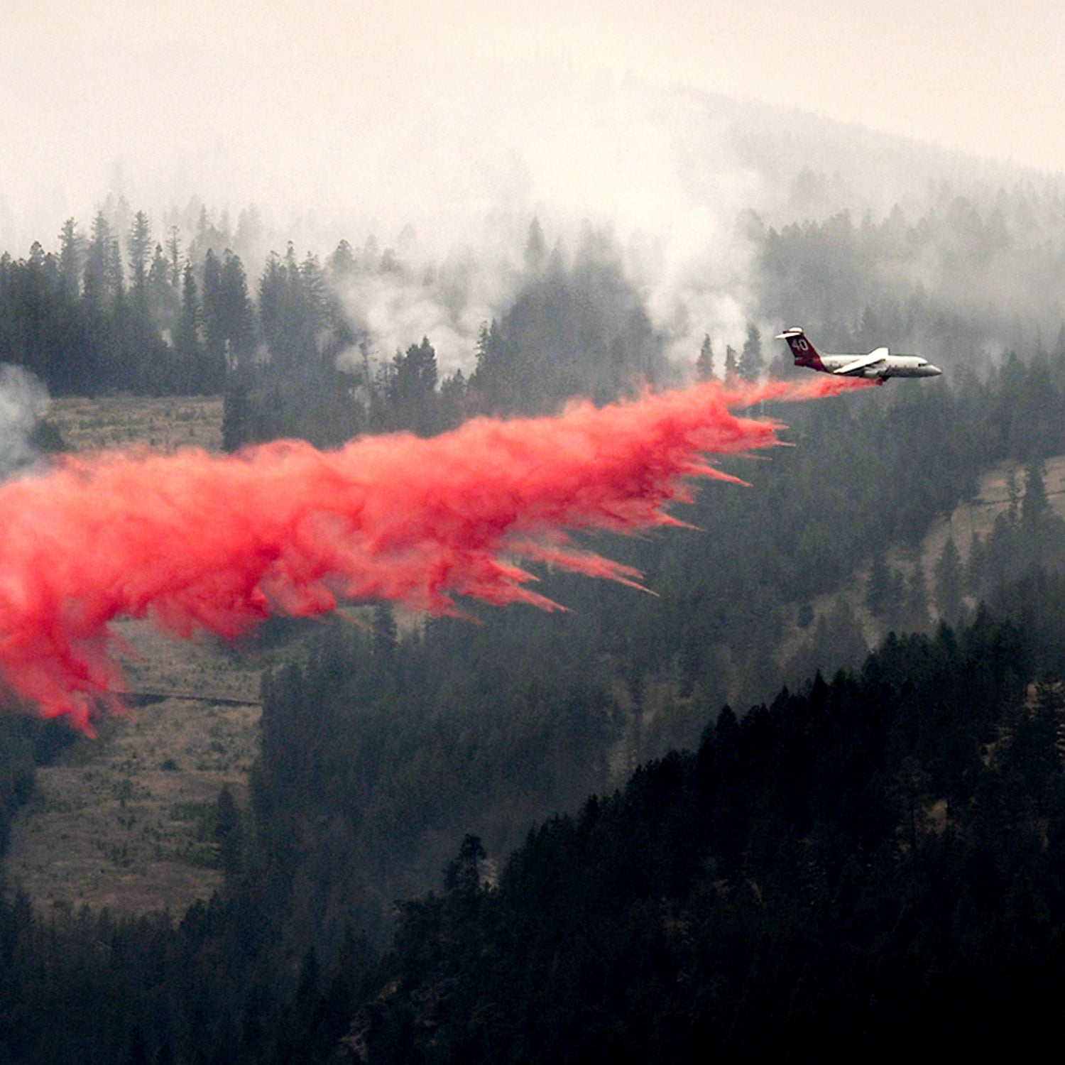 A bomber drops a load of fire retardant below the Lolo Peak fire creeping down the face of the ridge toward the Bitterroot Valley, Friday, Aug. 18, 2017 in Missoula, Mont. more homes west of the town of Lolo.