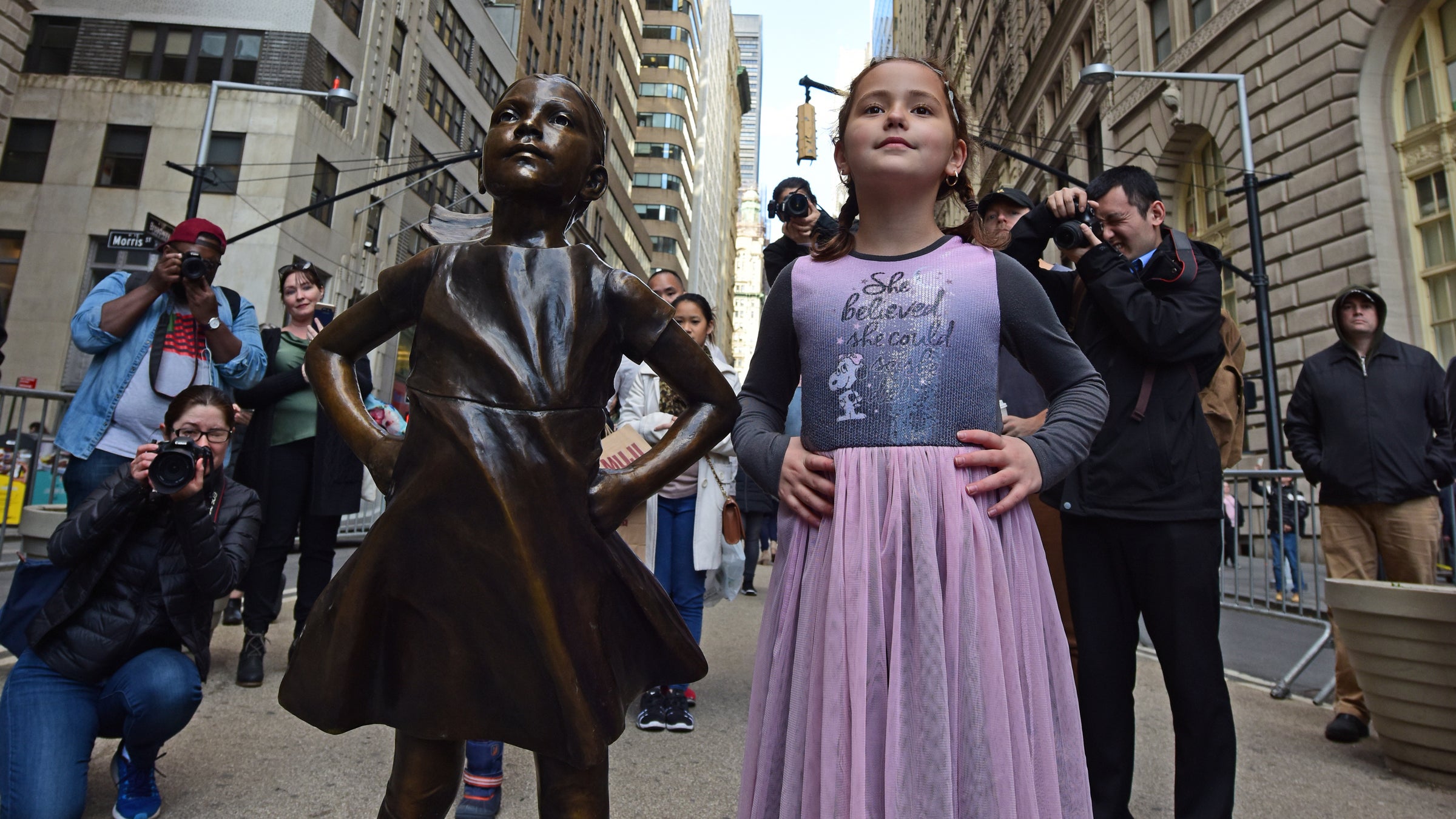 A young woman takes inspiration from Wall Street's "Fearless Girl" statue, placed opposite the iconic Bull statue.