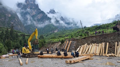 Local construction crews work to upgrade Zhagana's dirt parking lot, located at the base of the village.