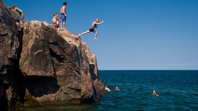 A girl jumps into Lake Superior from the rocky shore of Little Presque Isle in the Upper Peninsula of Michigan.