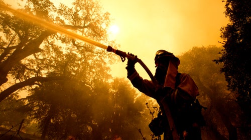 Napa County firefighter Jason Sheumann sprays water on a home as he battles flames from a wildfire Monday.