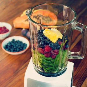 Fruits and vegetables as ingredients for a healthy smoothie: papaya, figs, lemon, blueberries, pomegranate seeds, raspberries, pineapple and baby spinach