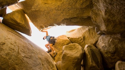 Russell Moore climbs through an open ended granite boulder cave in Anza Borrego State Park. California