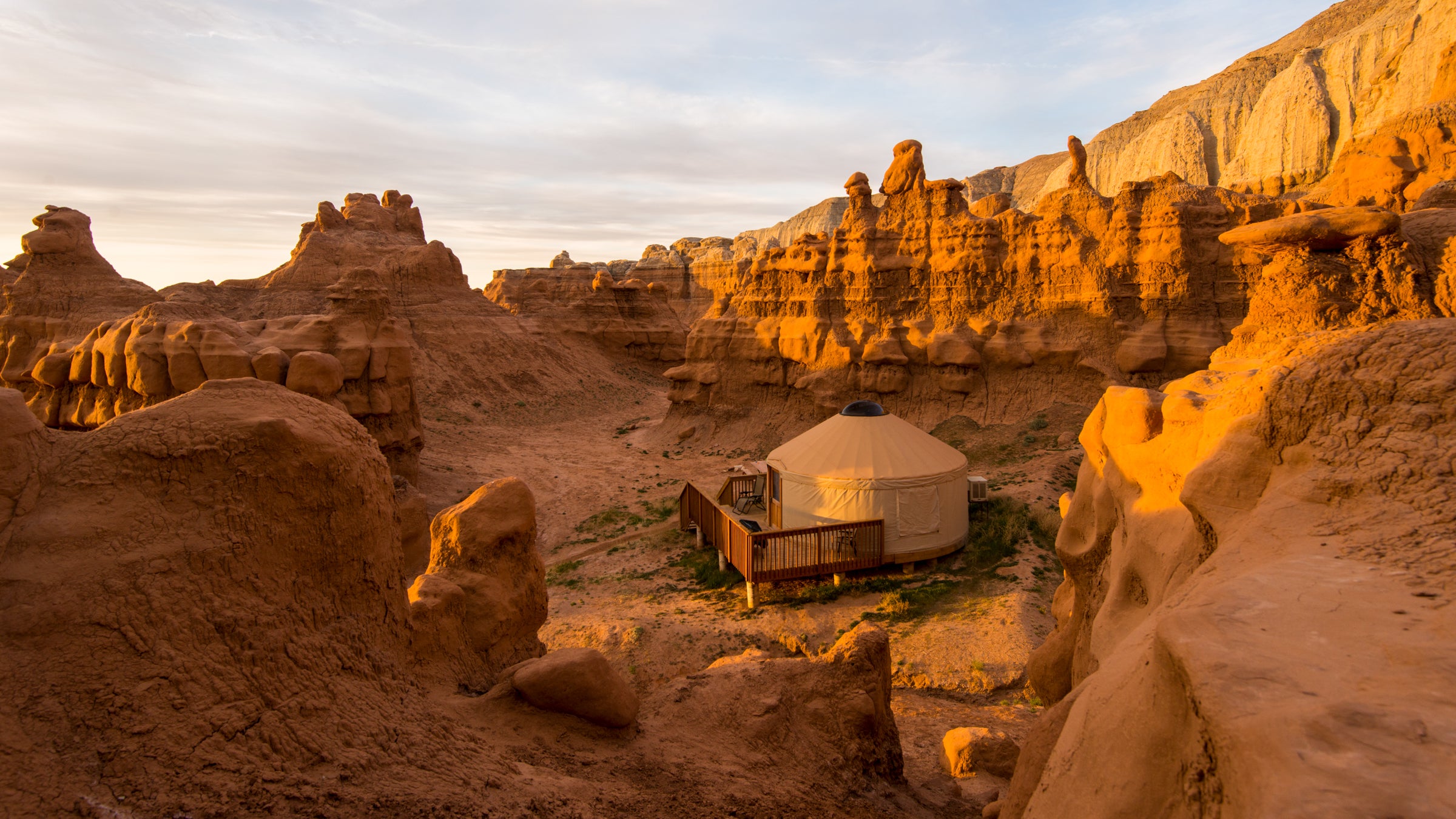 Sunrise hits a yurt below the red-rock cliffs of Goblin Valley.