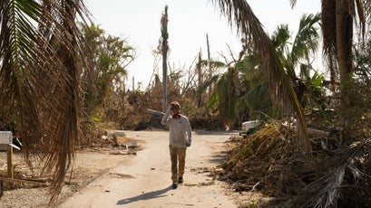 Will Benson walks between piles of debris after clearing a property.