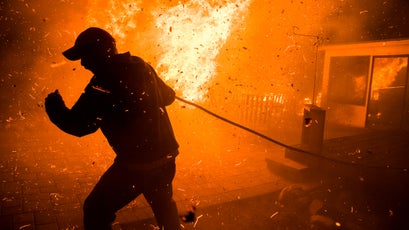 Jack Oren, a 50-year resident of La Conchita, south of Carpinteria, uses a garden hose to fight flames from the Thomas Fire. Strong Santa Ana winds sent a wall of fire into the subdivision adjacent to the 101 Freeway and the Pacific Ocean.