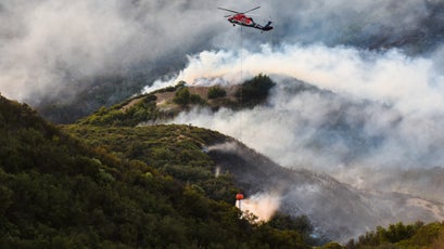 A privately contracted helicopter drops a bucket of water on the Thomas Fire in Los Padres National Forest near Ojai, December 9, 2017.