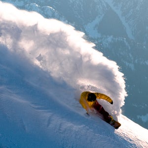 A snowboarder throws some spray during magic hour in the Whistler backcountry, BC, Canada.