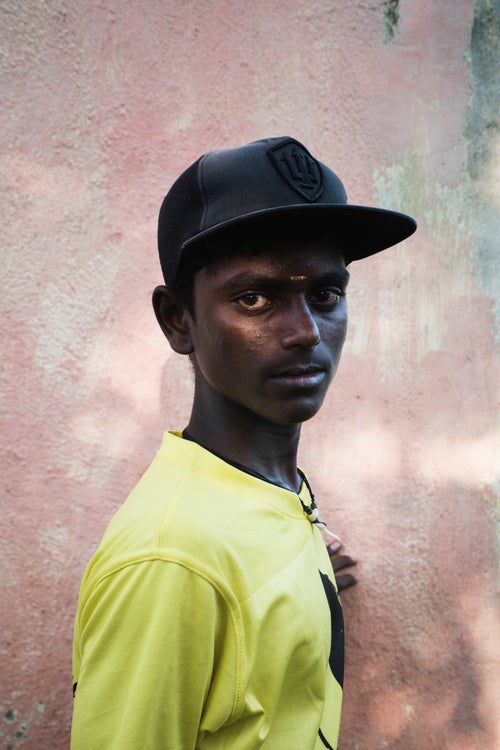 Nithish, age 16, leans against a wall during a sun filled evening near his home in the Fisherman Colony. Nithish, who comes from a fishing family, is the leading member of a group called the Sea Sharks. The Sea Sharks, consisting of around fifteen local surfers, serve as a comprehensive support group amongst themselves, helping each other during competitions, loaning equipment and inspiring each other to surf.