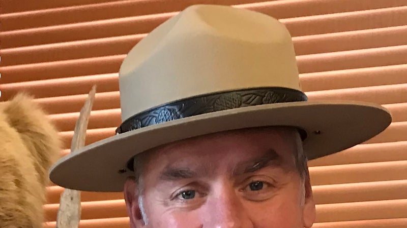 A closer look reveals the lack of the "USNPS" embossing on the band, and you can see a brass button on Zinke's right side.