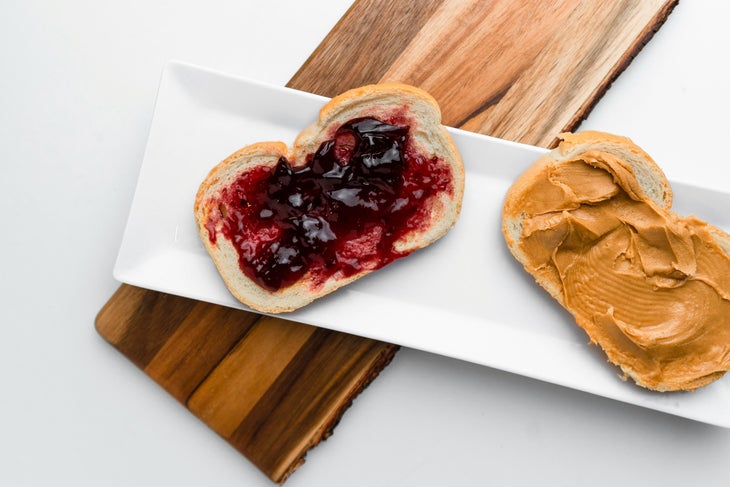 an open-faced peanut butter and jelly sandwich on a white plate