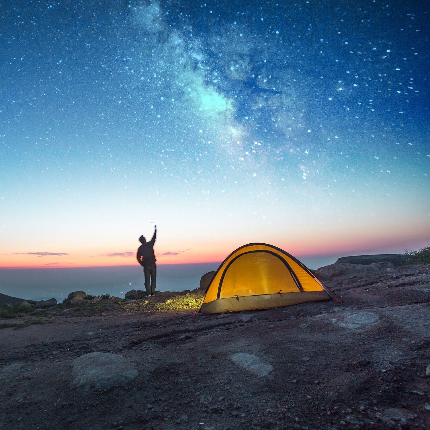 A light painting of a woman doing yoga next to her tent and