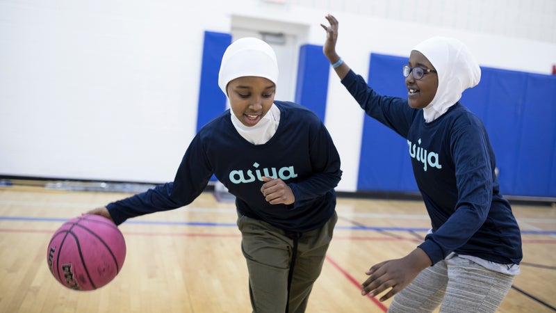 Nabhaii Farah, 12, (with ball) plays basketball with Amal Elmi, 12, at Brian Coyle Community Center.