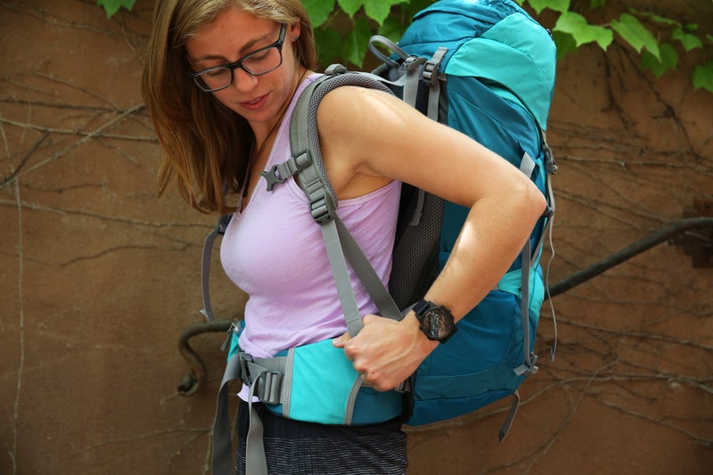 a woman fitting her backpack for a hike