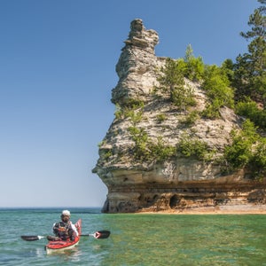 A kayaker approaches Miners Castle the signature rock formation of Pictured Rocks National Lakeshore on Lake Superior near Munising, Michigan.