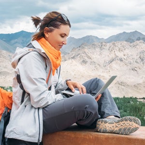 Woman with backpack on laptop outside
